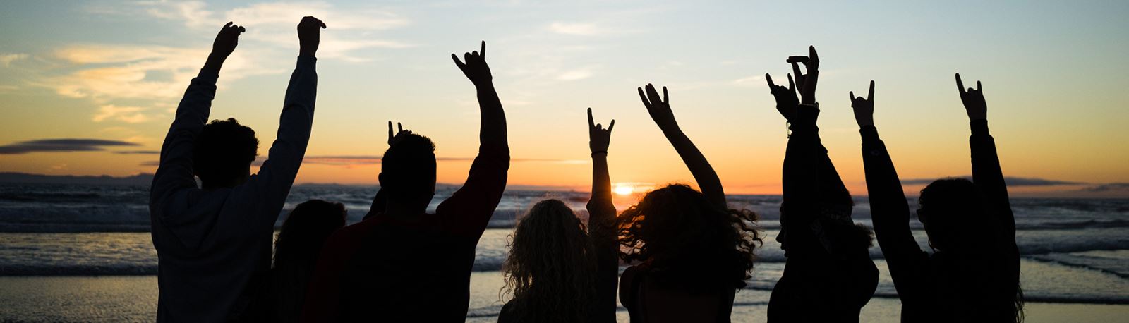 The silhouettes of 7 UCI students against a beach sunset background